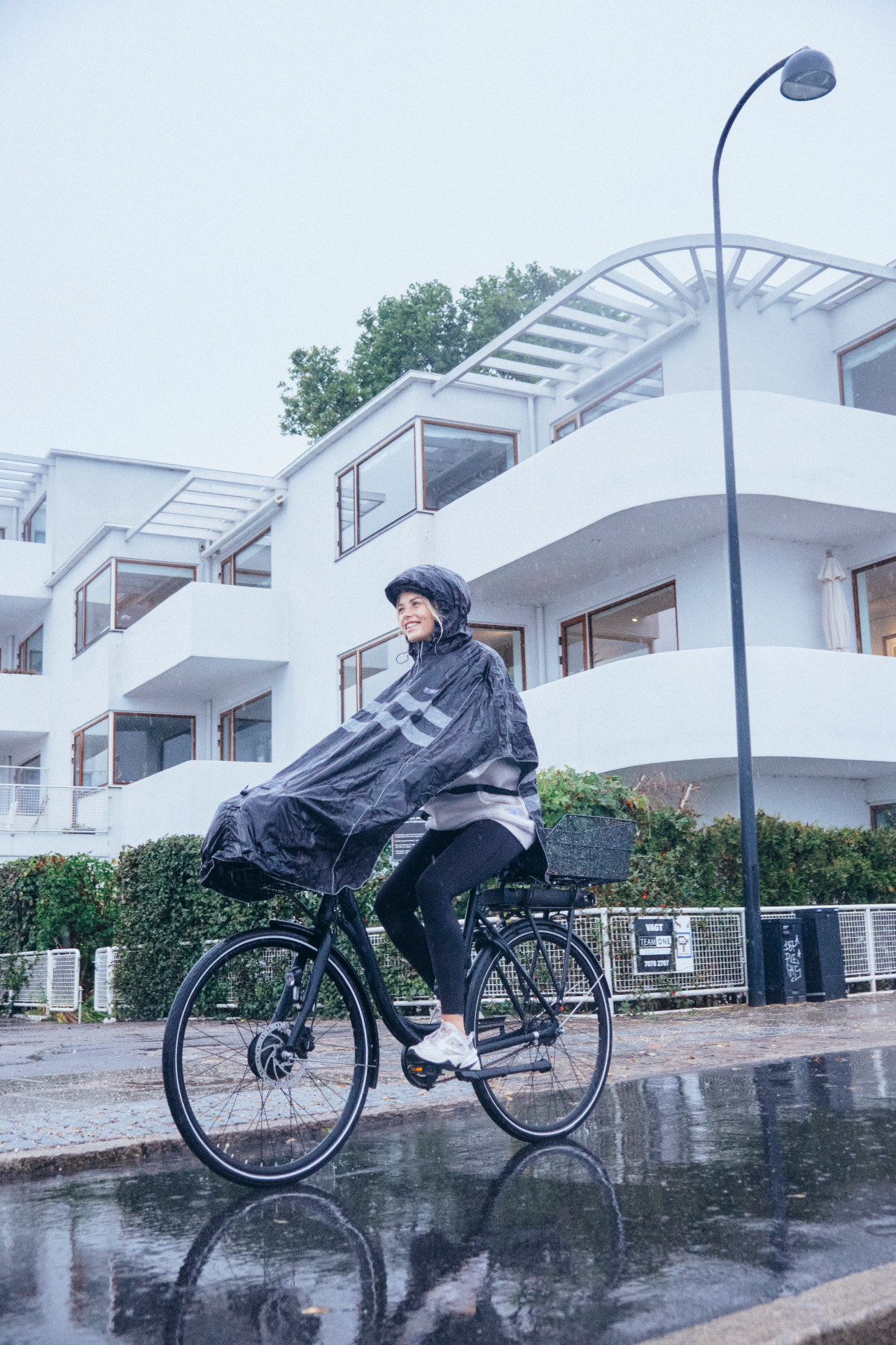 Cyklist i sort NoRain regnponcho på en våd gade i København